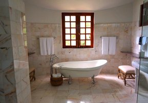 Badezimmer mit Marmorfliesen und Vintage-Badewanne in der Mitte